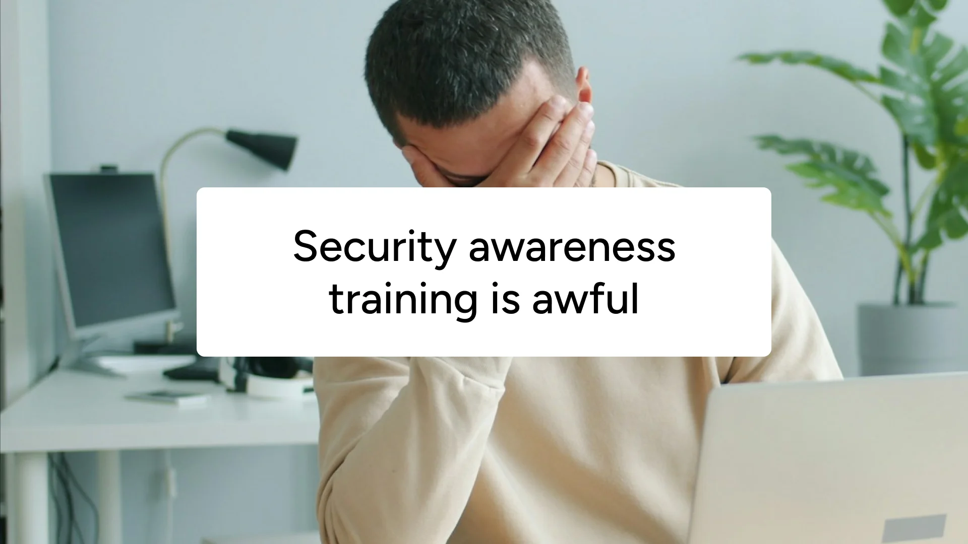 A man covering his face at his desk, captioned 'Security awareness training is awful'.
